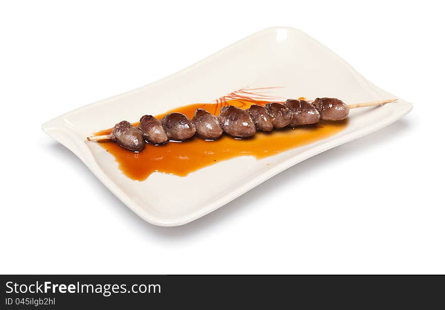 Grilled Chicken Heart on a skewer with sauce on a white plate on white background