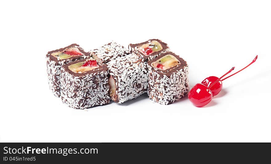 Chocolate roll with fruit filling sprinkle coconut with two cherries on a white background. The traditions of cuisine in Japan. Chocolate roll with fruit filling sprinkle coconut with two cherries on a white background. The traditions of cuisine in Japan