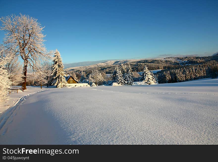 Picturesque winter landscape, winter landscape of the Eagle Mountains, sunny winter day in the landscape, snow-covered landscape in the setting sun, snow-covered cottage in the countryside. Picturesque winter landscape, winter landscape of the Eagle Mountains, sunny winter day in the landscape, snow-covered landscape in the setting sun, snow-covered cottage in the countryside