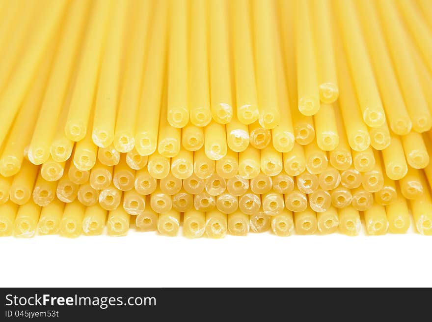 A close-up shot of raw perciatelli pasta on a white background. A close-up shot of raw perciatelli pasta on a white background