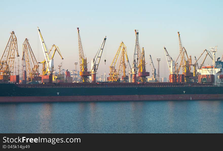 Commercial docks at sunset with a ship and cranes