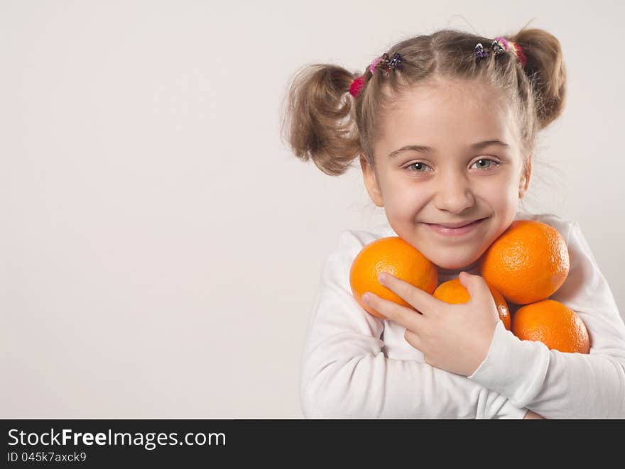 Little girl holding many oranges