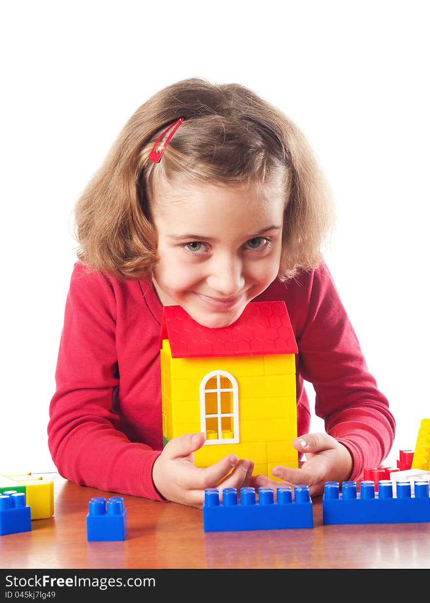 Cute little girl is constructing a house using building blocks