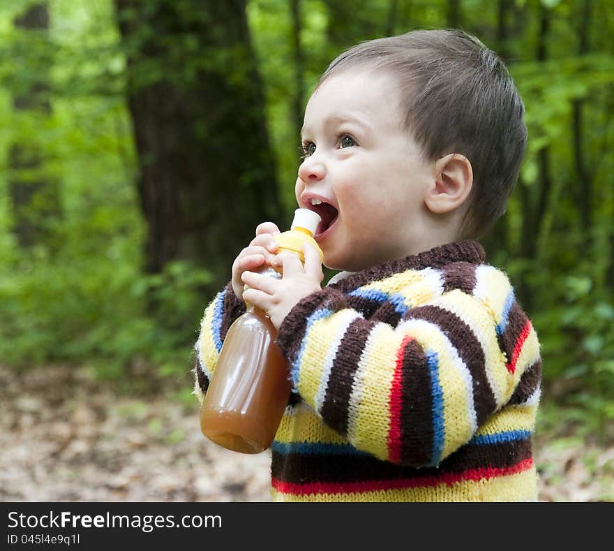 An outdoor portrait of a child toddler, boy or girl, in a forest drinking soft drink from a plastic bottle. An outdoor portrait of a child toddler, boy or girl, in a forest drinking soft drink from a plastic bottle.