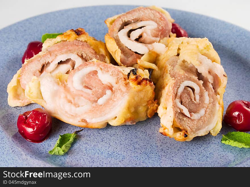 Baked pork rolls in puff pastry with cherry on blue plate. Baked pork rolls in puff pastry with cherry on blue plate