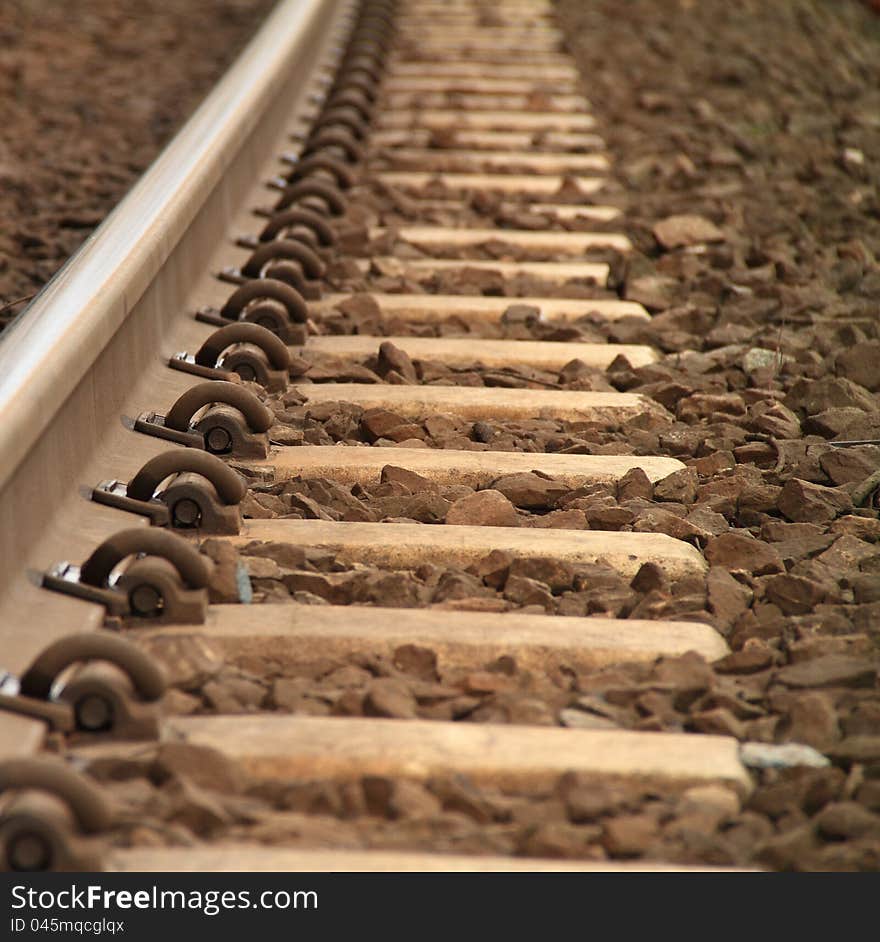 A low angle photo of a rusty railway track and it's tie downs.