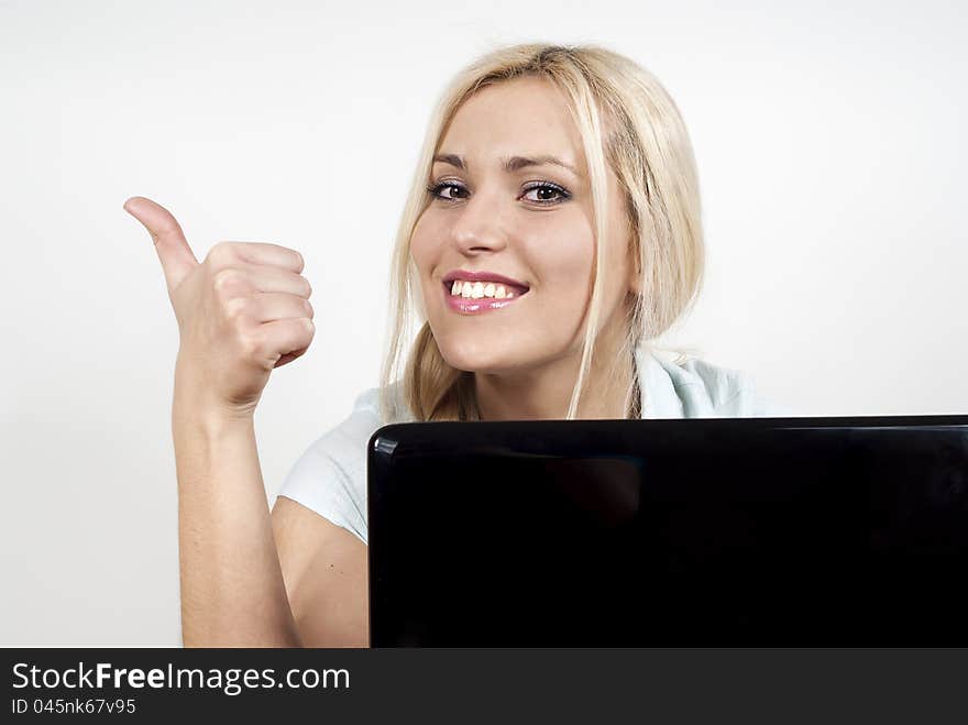 Beautiful girl sitting at a laptop computer and displays ok on the background of