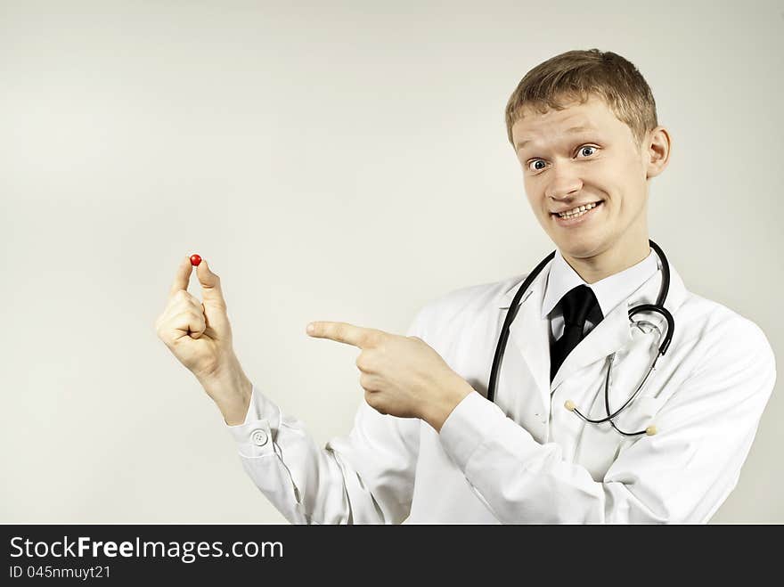 The guy doctor indicates the pill on the background of. The guy doctor indicates the pill on the background of