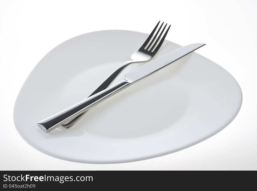 Fork and knife on a plate over white background