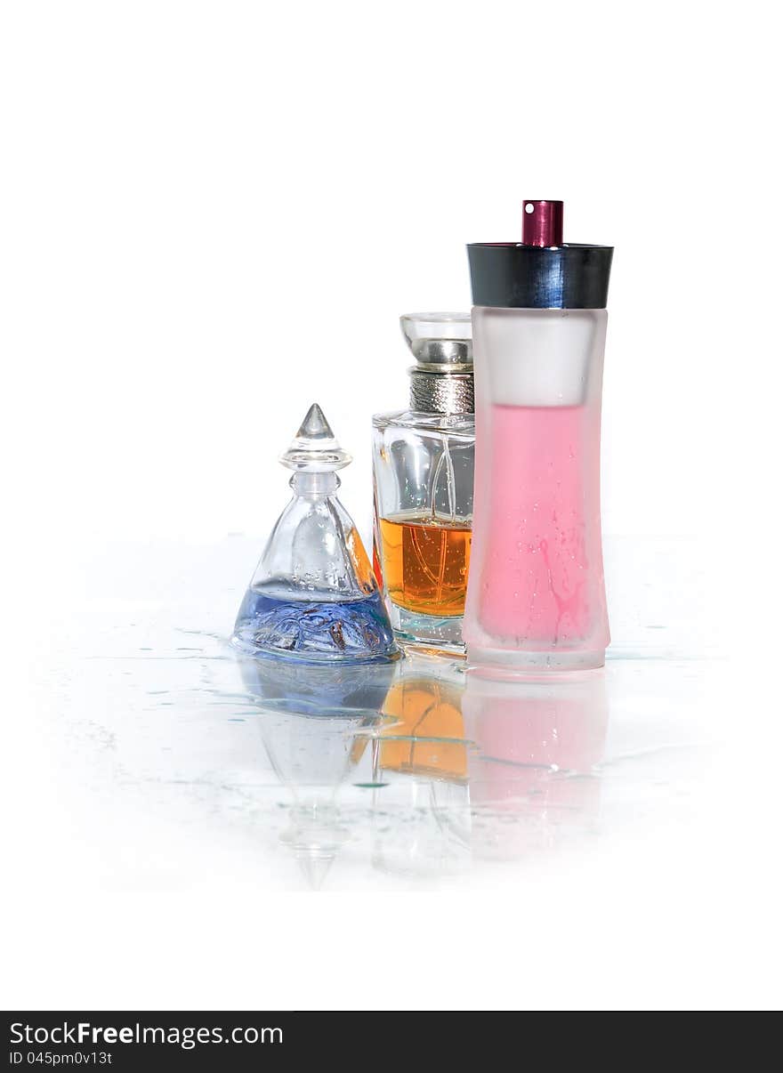 Three bottles of perfume standing on wet glass surface. Clipping path is included. Three bottles of perfume standing on wet glass surface. Clipping path is included