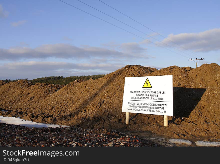 Warning sign standing near an excavation and warning about low voltage cables