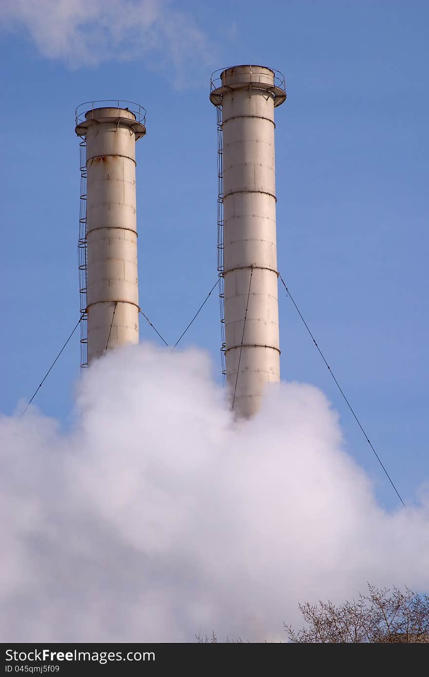 Industrial smoke pipes and white steam over blue sky. Industrial smoke pipes and white steam over blue sky