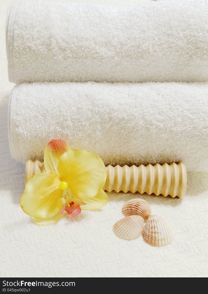 Foot massager with white folded towels, yellow orchid and seashells. Foot massager with white folded towels, yellow orchid and seashells