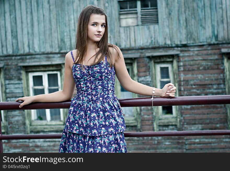 A girl stands near the old wooden house. A girl stands near the old wooden house