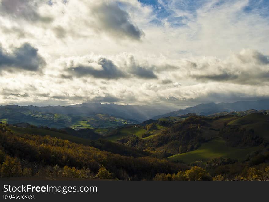 The sun tries to breach the clouds in a sunny Italian hills valley. The sun tries to breach the clouds in a sunny Italian hills valley