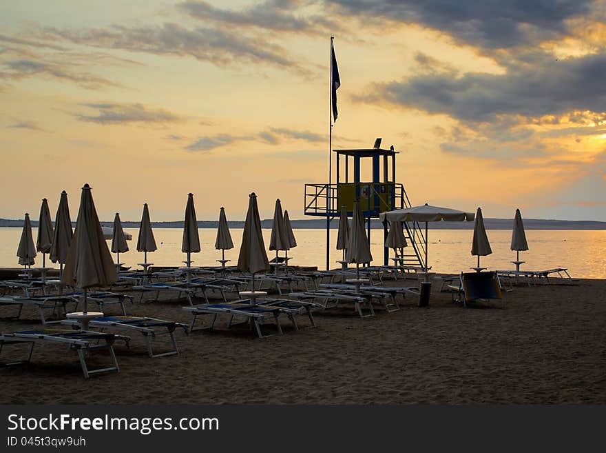 Evening sunset on beach with sun beds and guardian towers