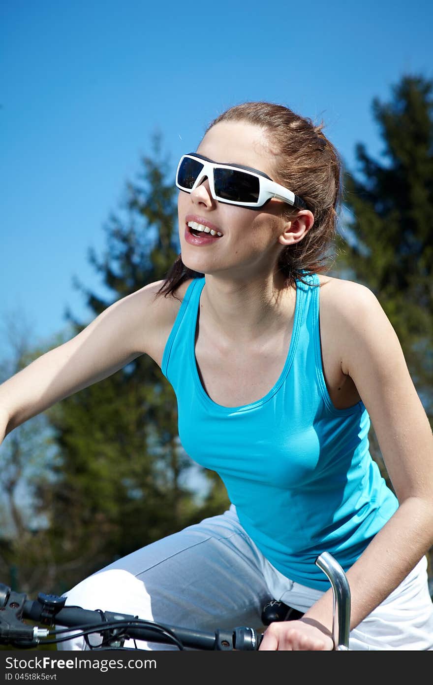 Young woman on a bicykle outdoors smiling