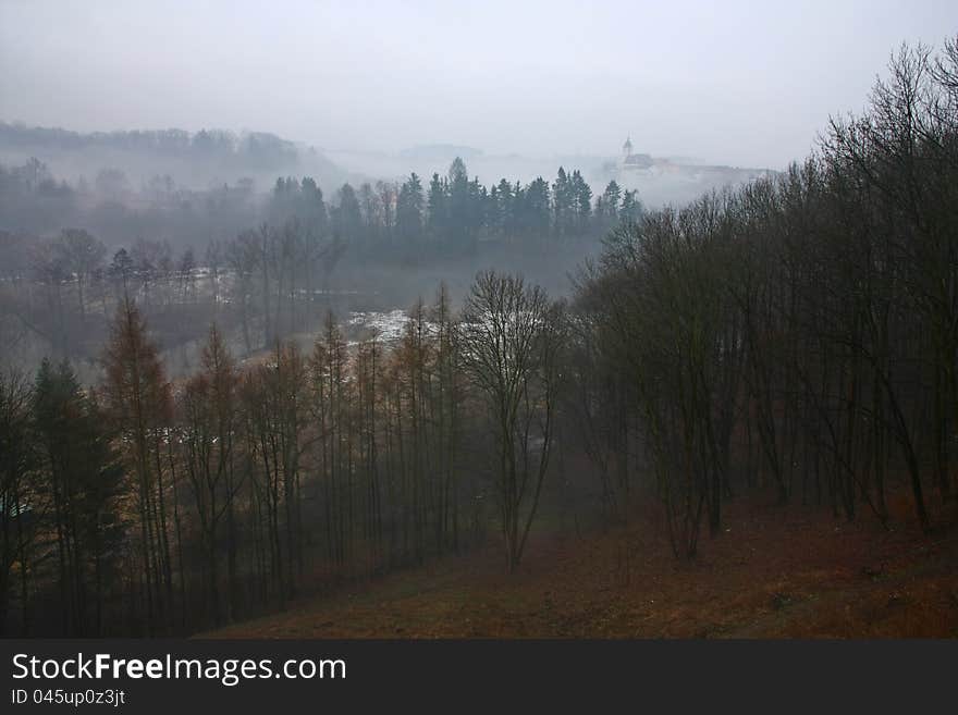 Hilly landscape in overcast day, city ​​on a hill in the background misty. Hilly landscape in overcast day, city ​​on a hill in the background misty