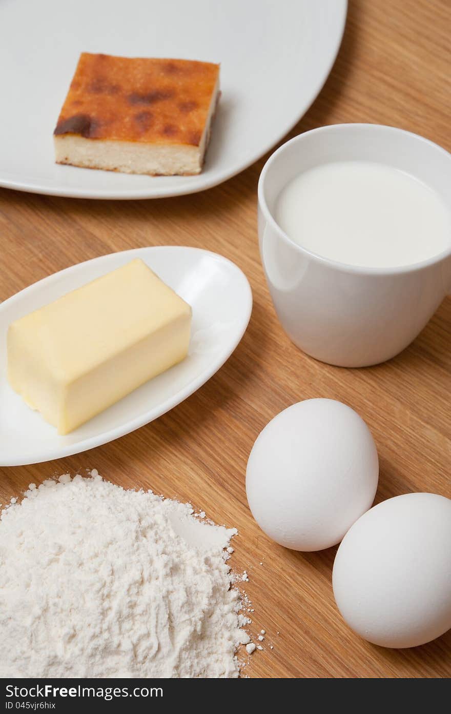 Flour with butter, milk and eggs on the wood table