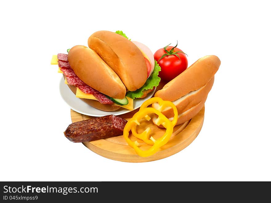 Sandwich with sausage and vegetables on plate, bread and vegetables on cutting board isolated on white background. Sandwich with sausage and vegetables on plate, bread and vegetables on cutting board isolated on white background