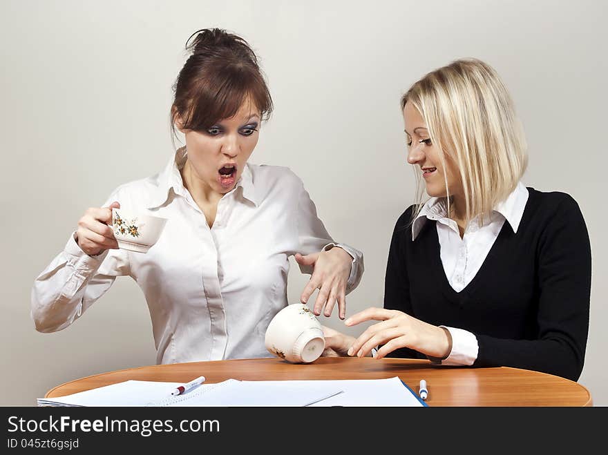 Beautiful girls screaming poured tea in the office at the table