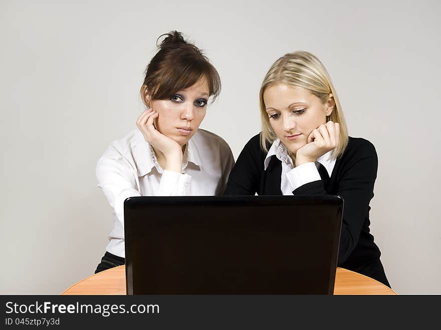 Beautiful girls upset look of the laptop at the table. Beautiful girls upset look of the laptop at the table