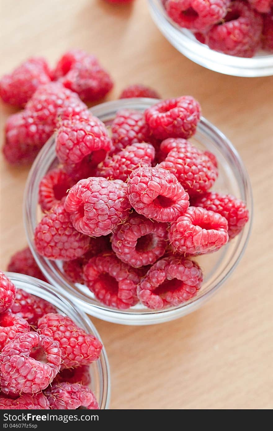 Bowl of raspberries on wooden table close up