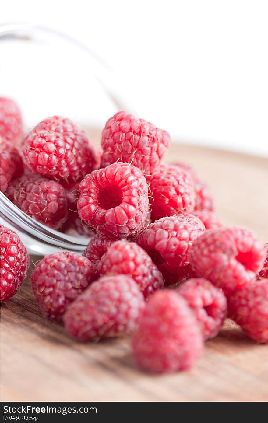 Bowl of raspberries on wooden table close up