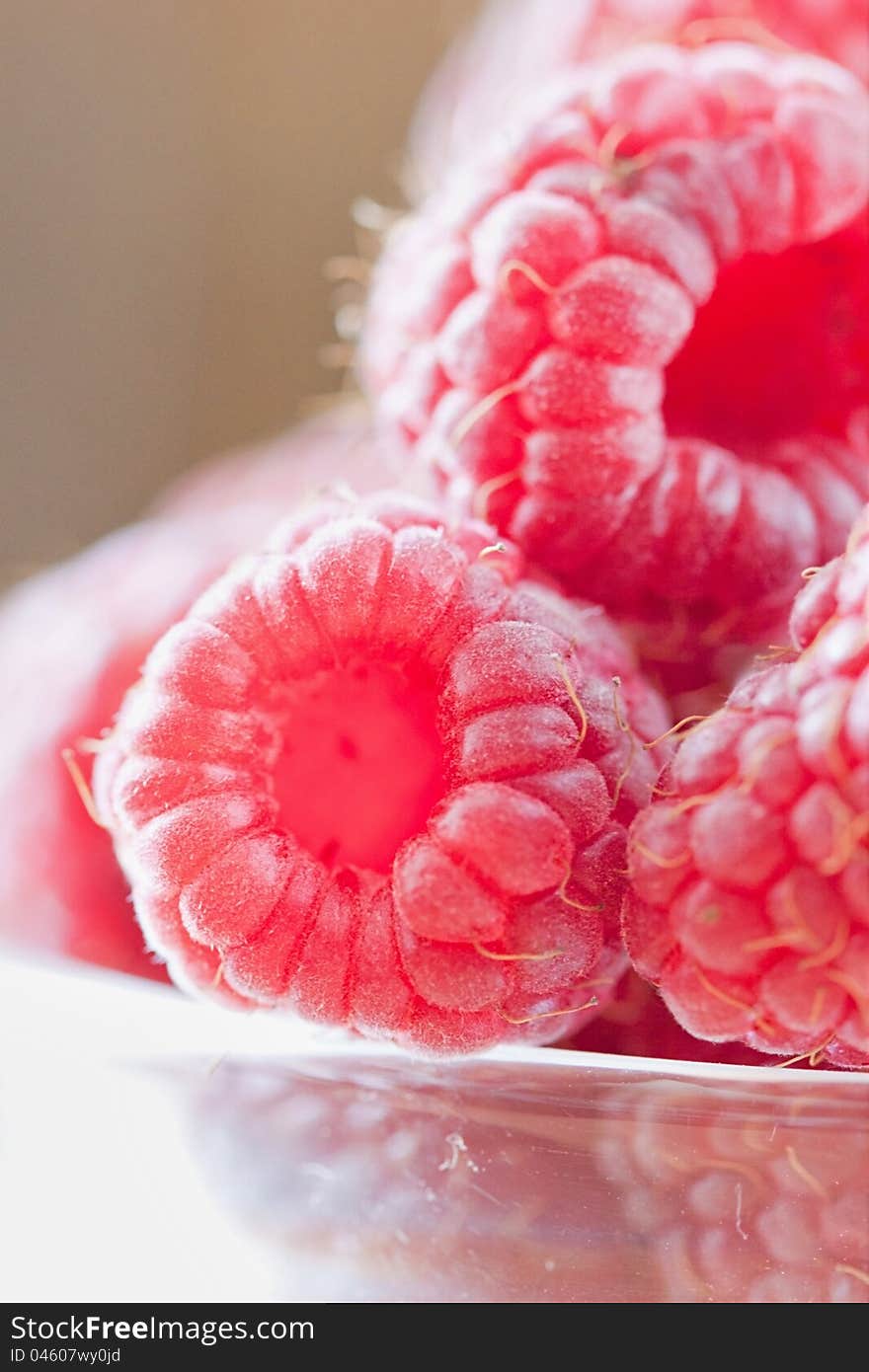 Bowl of raspberries on wooden table close up