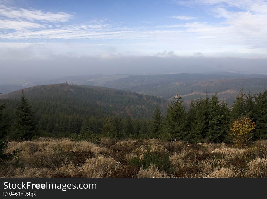 Mountain landscape with brown grass, hilly landscape with pine trees, the landscape in the mountains with blue sky, mountains, Czech Republic, Eagle Mountains in the Czech Republic. Mountain landscape with brown grass, hilly landscape with pine trees, the landscape in the mountains with blue sky, mountains, Czech Republic, Eagle Mountains in the Czech Republic