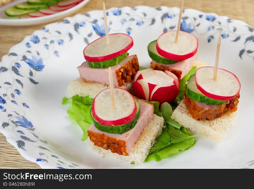 Canape with radishes, ham, cucumber on plate