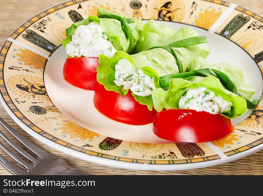 Tasty snack: lettuce stuffed with cheese and herbs, slices of tomatoes on plate