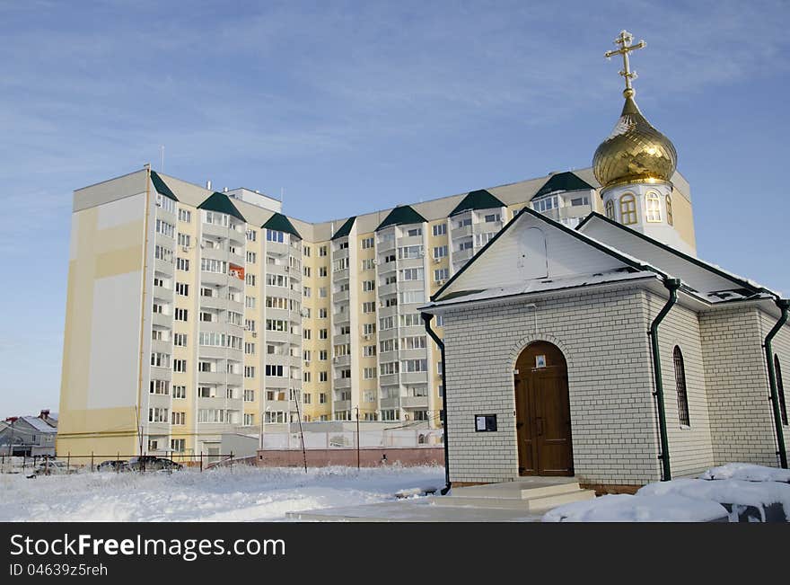 The Chapel with gold(en) dome on background new building in village Jubilee in city Saratov. The Chapel with gold(en) dome on background new building in village Jubilee in city Saratov.