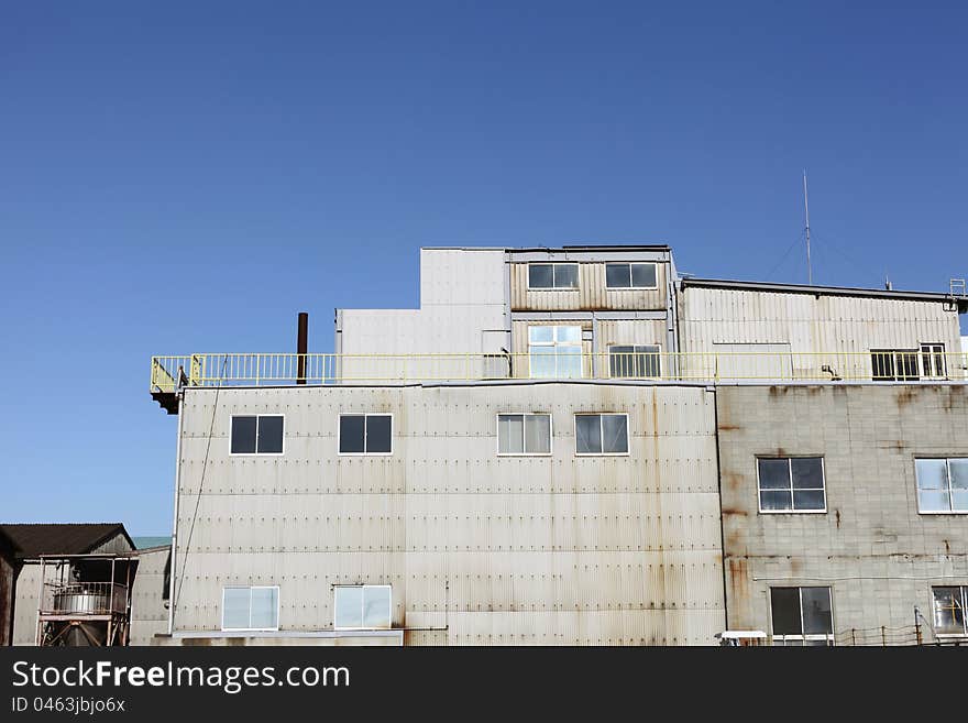 View of grunge factory against blue sky