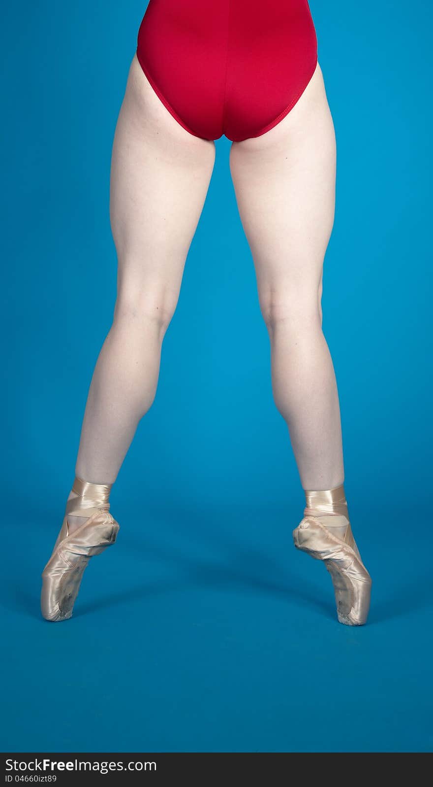 Back of Ballerina's Legs En Pointe Wearing a Red Leotard Against a Blue Background. Back of Ballerina's Legs En Pointe Wearing a Red Leotard Against a Blue Background