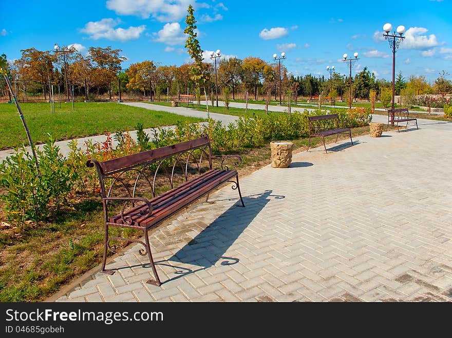 Autumn city park with benches, lawns, walkways, and lights