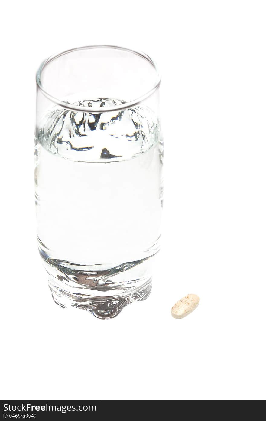 A glass of water and a tablet on a white background. A glass of water and a tablet on a white background.