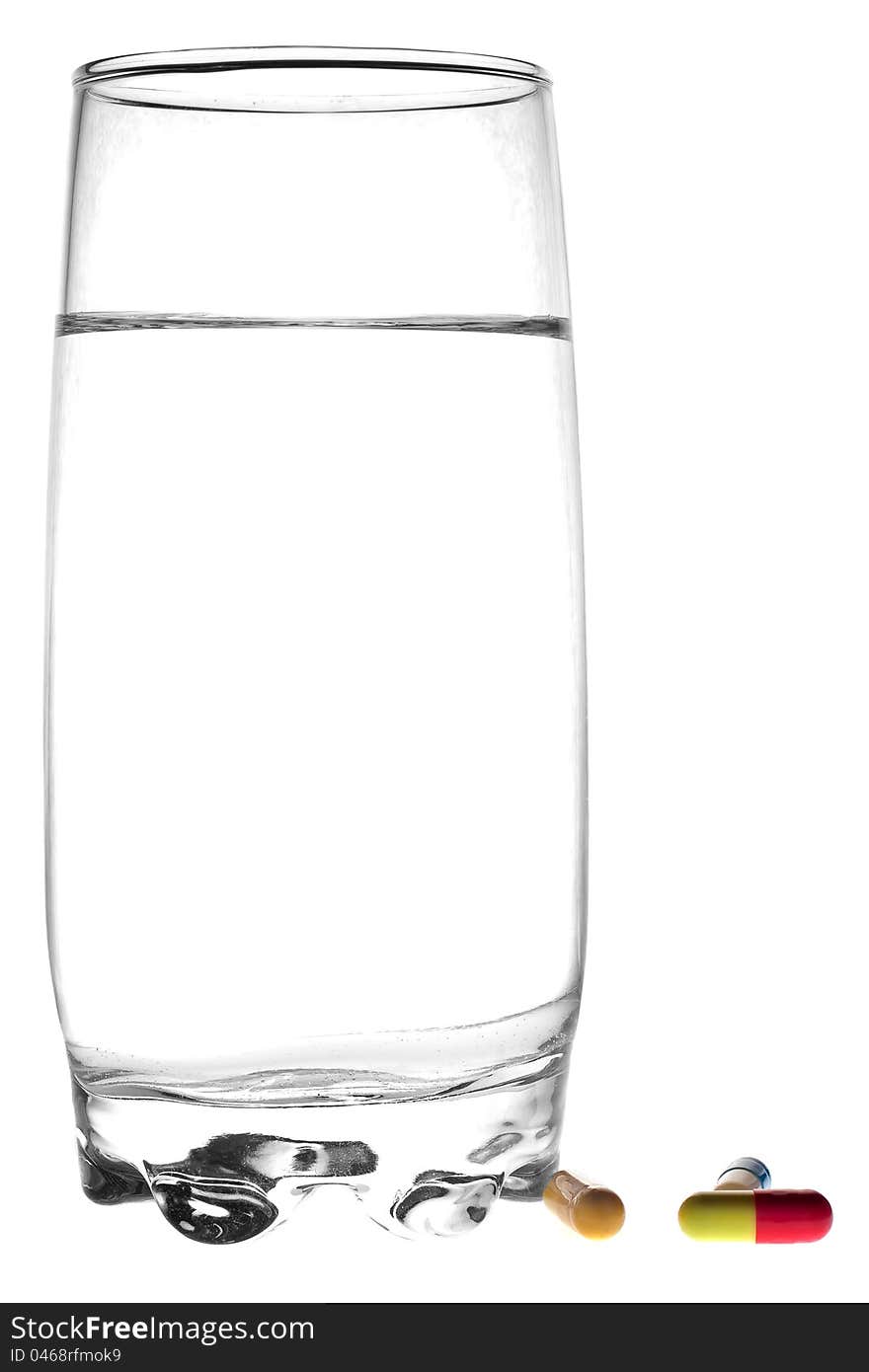 A glass of water and a tablets on a white background. A glass of water and a tablets on a white background.