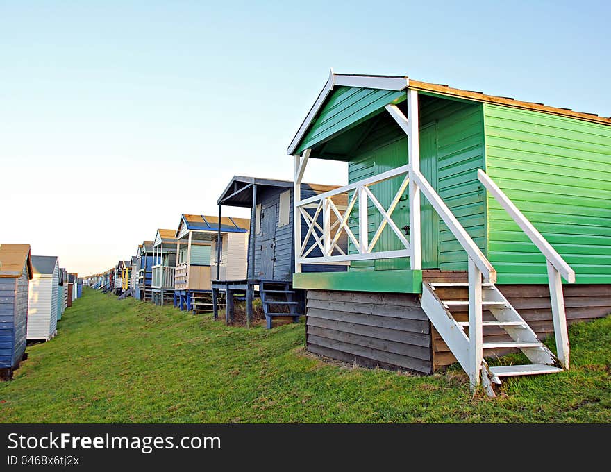 Photo of colourful beach huts all in a row on a kentish seaside town. Photo of colourful beach huts all in a row on a kentish seaside town.