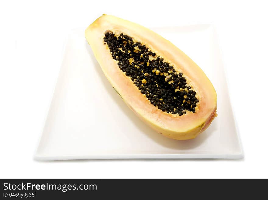 Half of the papaya fruit on a plate on a white background