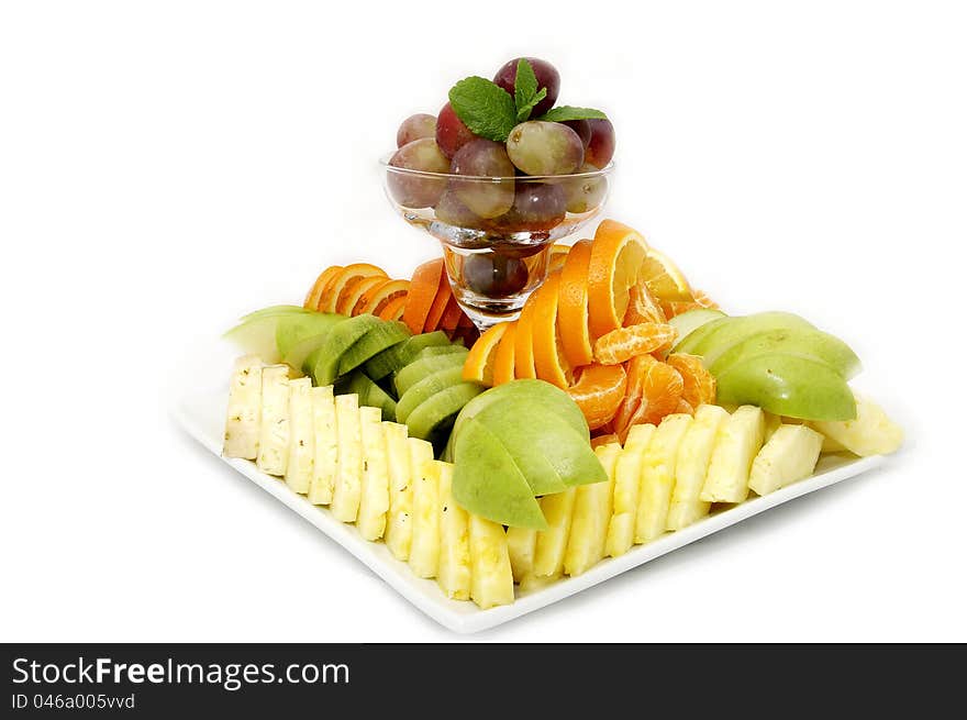 A plate of beautifully sliced fruit on white background. A plate of beautifully sliced fruit on white background