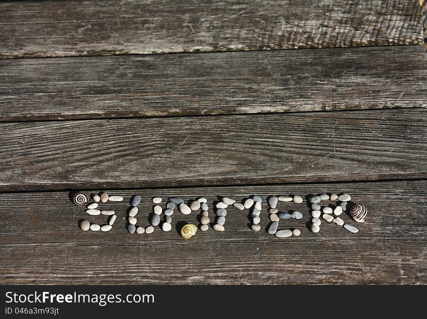 Summer word made of little stones on the beach bench