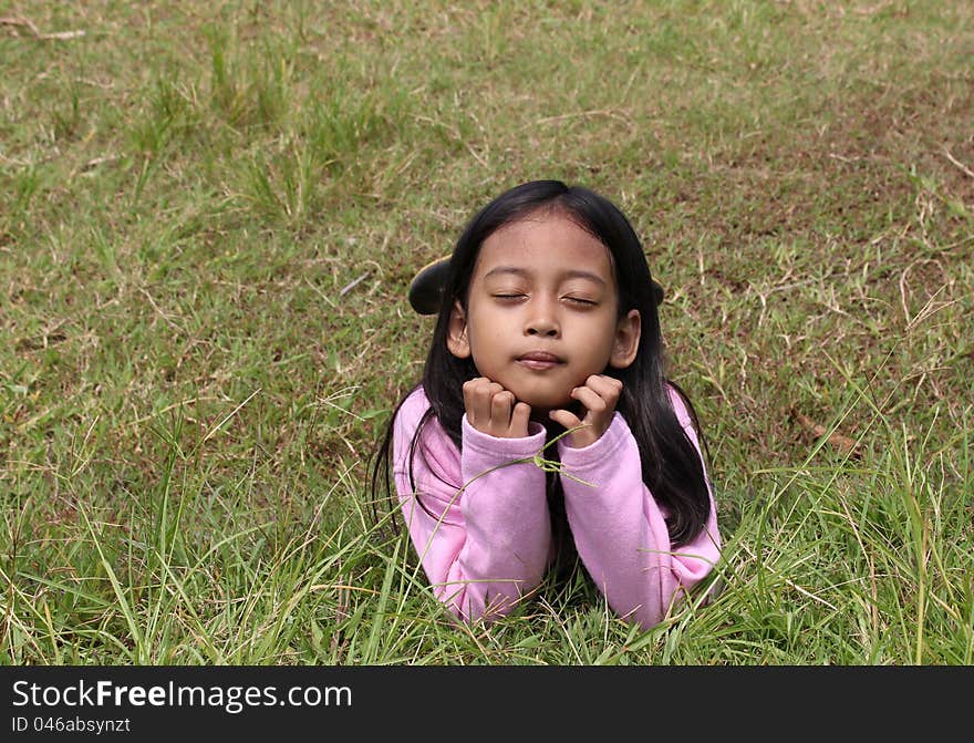 Little girl lying on green field of grass. Little girl lying on green field of grass.