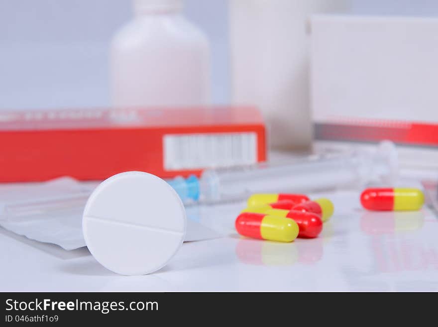 Different pills, packs and syringe on table, selective focus