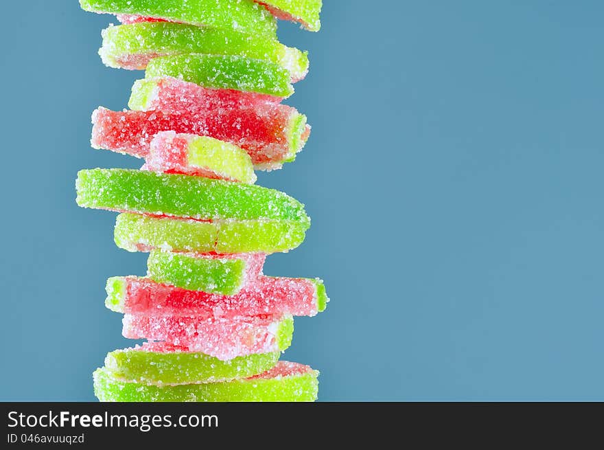 A stack of fruit jelly watermelon candies on a blue background with copy space. A stack of fruit jelly watermelon candies on a blue background with copy space