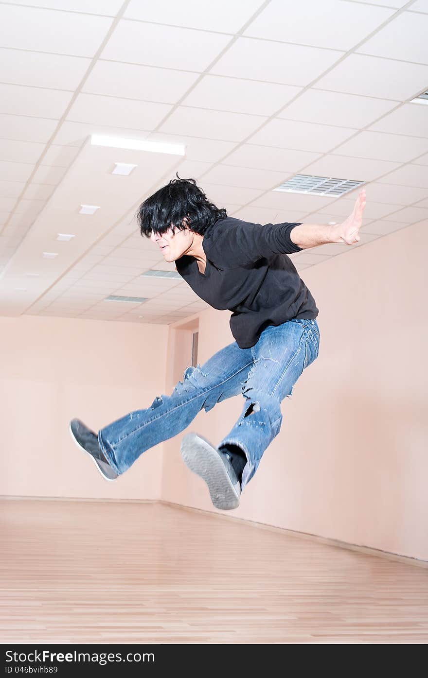 Young dancer man jumping trick in training hall