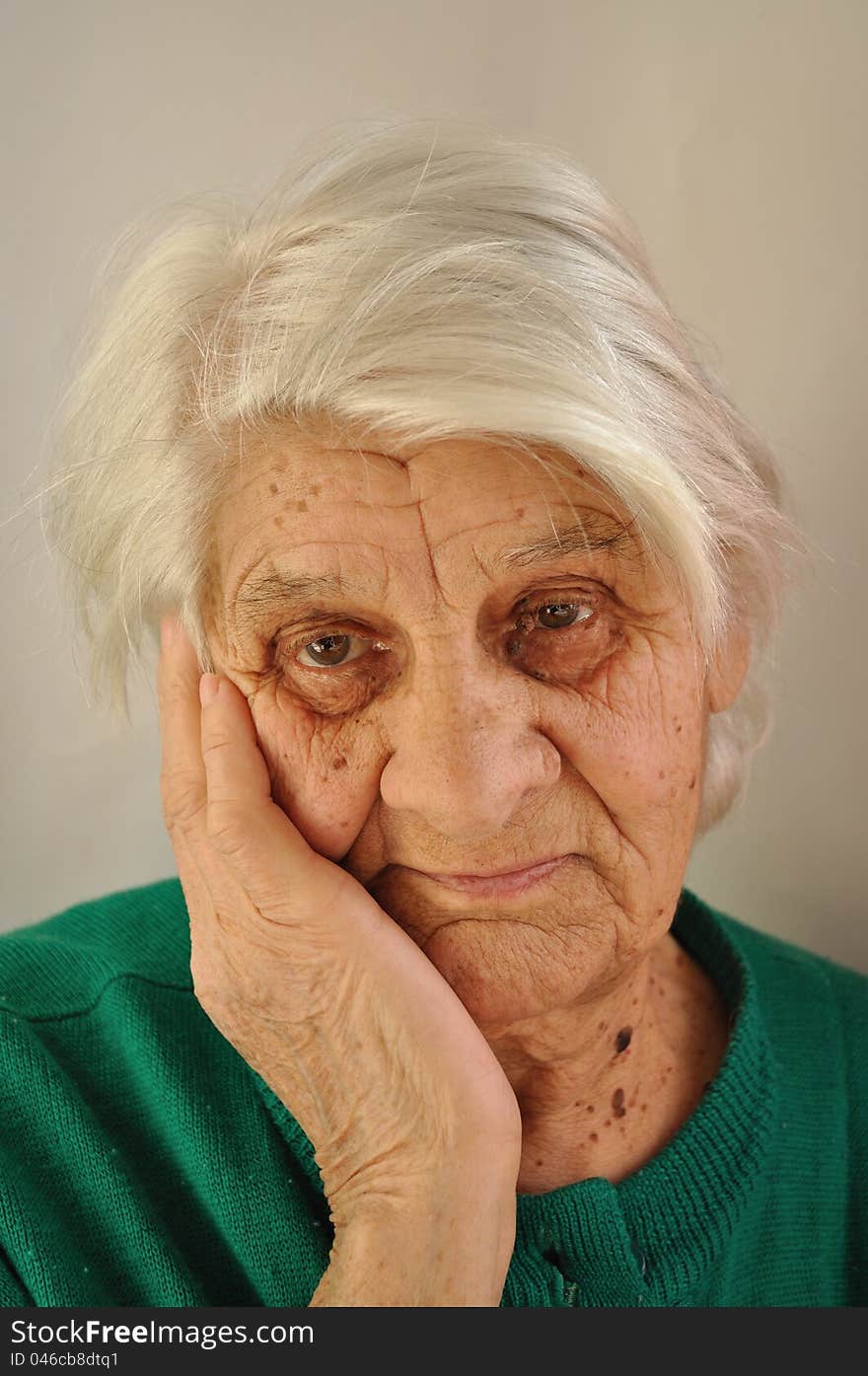 Elderly gray-haired woman with a sad thought, leaned her cheek on his hand. Elderly gray-haired woman with a sad thought, leaned her cheek on his hand