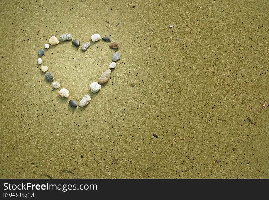 Heart made of small stones on sand