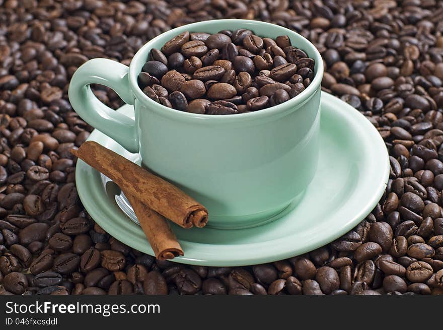 Coffee bean in the coffee cup served with cinnamon shot with coffee bean background. Coffee bean in the coffee cup served with cinnamon shot with coffee bean background