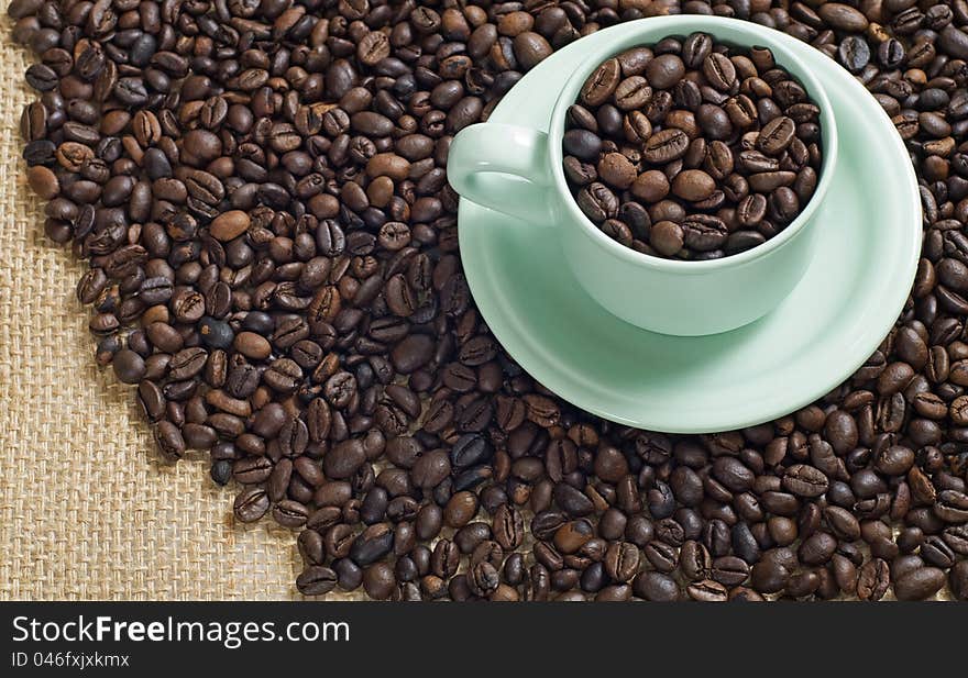 Coffee bean in the coffee cup shot with coffee bean and burlap background. Coffee bean in the coffee cup shot with coffee bean and burlap background